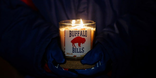 Una persona sostiene una vela de Buffalo Bills durante una vigilia con velas por la seguridad de Bills Damar Hamlin el martes 3 de enero de 2023 en Orchard Park, Nueva York.