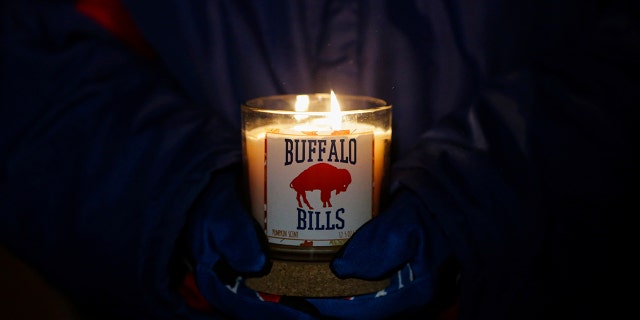 Una persona sostiene una vela de Buffalo Bills durante una vigilia con velas por la seguridad de Bills Damar Hamlin el martes 3 de enero de 2023 en Orchard Park, Nueva York.