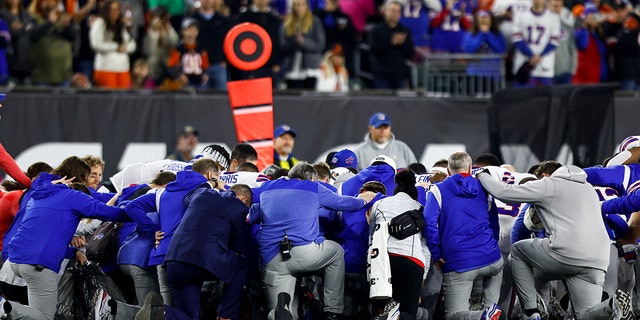 Los jugadores y el personal de los Buffalo Bills se arrodillan juntos en solidaridad después de que Damar Hamlin se lesionara durante el primer cuarto de un partido de fútbol americano de la NFL contra los Cincinnati Bengals el 2 de enero de 2023 en Cincinnati, Ohio.