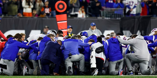 Los jugadores y el personal de los Buffalo Bills se arrodillan juntos en solidaridad después de que Damar Hamlin se lesionara durante el primer cuarto de un partido de fútbol americano de la NFL contra los Cincinnati Bengals el 2 de enero de 2023 en Cincinnati.