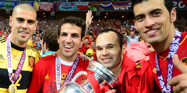 El portero español Víctor Valdés, el centrocampista español Cesc Fábregas, el centrocampista español Andrés Iniesta y el centrocampista español Sergio Busquets posan con el trofeo después de ganar el partido final de la Eurocopa 2012 entre España y Italia el 1 de julio de 2012 en el Estadio Olímpico de Kyiv.