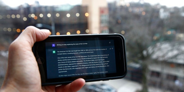 A ChatGPT hint is displayed on a device outside a public school in Brooklyn, New York, Thursday, January 5, 2023. This week, New York City school authorities began blocking an impressive but controversial writing tool that can generate paragraphs of human-like text. .  . 