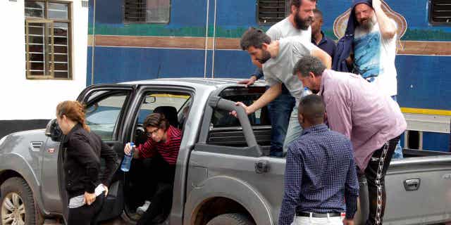 Seven of the eight Croatian nationals charged with attempting to traffic children exit a vehicle outside the magistrate's court in Ndola, Zambia, on Jan. 10, 2023. The Croatian nationals have pleaded not guilty to the charge of child trafficking.