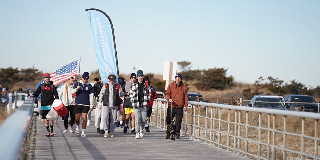 Swimmers make their way down the "Sunday Swim red carpet" to the beach on Jan. 8, 2023.
