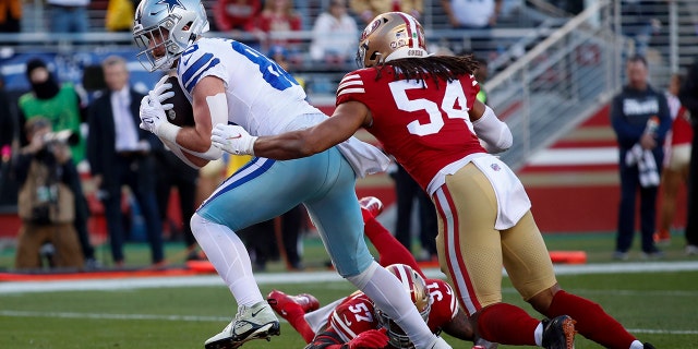 Dallas Cowboys tight end Dalton Schultz, left, scores a touchdown past San Francisco 49ers linebacker Fred Warner. #54, and linebacker Dre Greenlaw, #57, during the first half of an NFL divisional round playoff football game in Santa Clara, California, Sunday, Jan. 22, 2023.