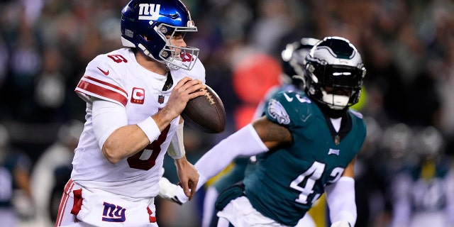 El mariscal de campo de los New York Giants, Daniel Jones, a la izquierda, corre con el balón mientras el linebacker de los Philadelphia Eagles, Kyzir White, lo persigue durante la primera mitad de un partido de fútbol americano de la Ronda Divisional de la NFL, el sábado 21 de enero de 2023, en Filadelfia. 