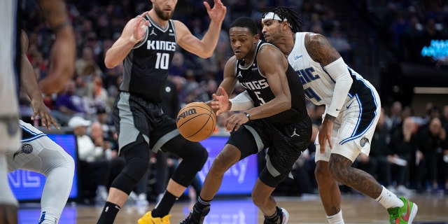 Orlando Magic guard Gary Harris, #14, strips the ball from Sacramento Kings guard De'Aaron Fox, #5, in the second half of an NBA basketball game in Sacramento, California, on Monday, January 9, 2023. 