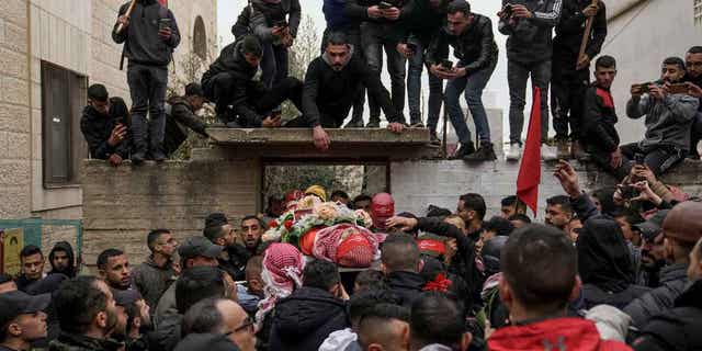 Mourners carry the body of 14-year-old Palestinian Omar Khumour during his funeral in the West Bank city of Bethlehem on Jan. 16, 2023. The Israelis also deported an Italian activist after arresting her during the same raid.