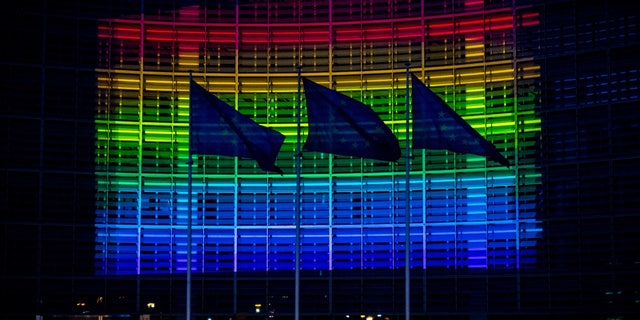 European Commission HQ with flags, lit up in rainbow colors