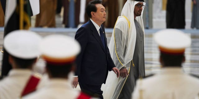 South Korean President Yoon Suk Yeol, center left, and Emirati leader Sheikh Mohammed bin Zayed Al Nahyan walk past an honor guard at Qasar Al Watan in Abu Dhabi, United Arab Emirates, Sunday, Jan. 15, 2023. Yoon received an honor guard welcome Sunday on a trip to the United Arab Emirates, where Seoul hopes to expand its military sales while finishing its construction of the Arabian Peninsula's first nuclear power plant. (AP Photo/Jon Gambrell)