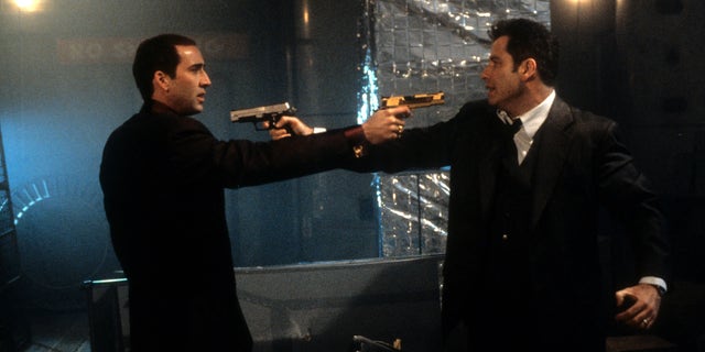Nicolas Cage and John Travolta aiming guns at each other in a scene from 