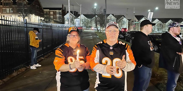 Los fanáticos de los Cincinnati Bengals, Janet y Chuck Kohl, sostienen velas afuera del hospital donde la seguridad de los Buffalo Bills, Damar Hamlin, fue trasladada de urgencia después de colapsar en el campo y requerir RCP.