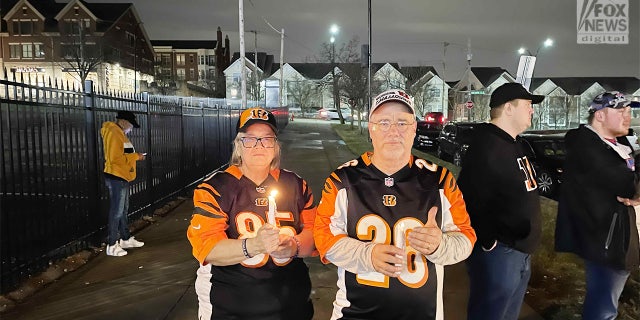 Los fanáticos de los Cincinnati Bengals, Janet y Chuck Kohl, sostienen velas afuera del hospital donde la seguridad de los Buffalo Bills, Damar Hamlin, fue trasladada de urgencia después de colapsar en el campo y requerir RCP.