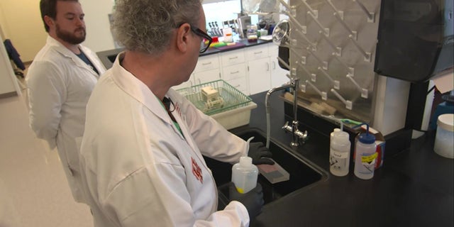 Dr. Colin Haile (center, wearing glasses) is seen here cleaning a sample in his lab at the University of Houston. He believes the fentanyl vaccine his team developed could help people recover from their addiction.