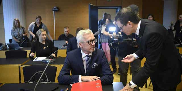 Editor-in-chief of Helsingin Sanomat Kaius Niemi, right, speaks with his lawyer Kai Kotiranta, left, ahead of the hearing for the Helsingin Sanomat journalists who are accused of disclosing state secrets in Helsinki, on Aug. 25, 2022. 