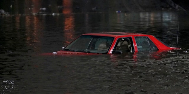 An empty vehicle is surrounded by floodwaters on a road in Oakland, Calif., Wednesday, Jan.  4, 2023. Another winter storm moved into California on Wednesday, walloping the northern part of the state with more rain and snow.  It's the second major storm of the week in the parked state. 