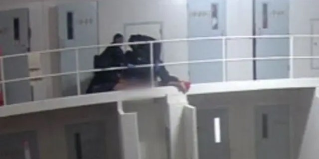 Officers hold Terry Lee Thurmond down to the ground, appearing to kneel on his back, neck and shoulders. Thurmond appears to begin hanging over the 2nd floor railing.