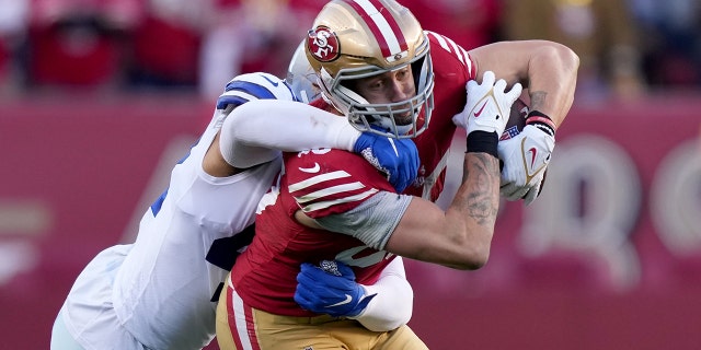 El ala cerrada de los San Francisco 49ers, George Kittle, es abordado por el apoyador de los Dallas Cowboys, Anthony Barr, durante el partido de playoffs de la Ronda Divisional de la NFC en el Levi's Stadium el 22 de enero de 2023 en Santa Clara, California.