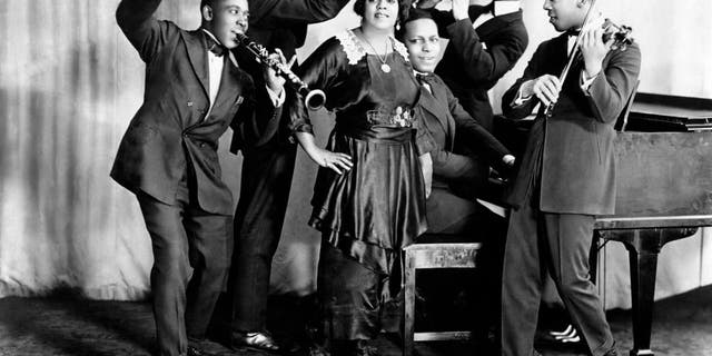 Jazz and blues singer Mamie Smith and Her Jazz Hounds (including Willie "The Lion" Smith on piano) pose for a portrait circa 1920 in New York City. Smith performed "Crazy Blues," the first blues hit record, with Her Jazz Hounds in 1920. 