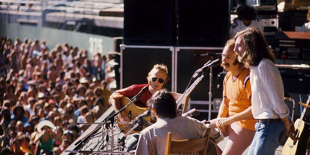 (LR) Stephen Stills, Neil Young, David Crosby and Graham Nash of Crosby Stills Nash & Young perform on stage at Oakland Coliseum on July 13, 1974 in Oakland, California.
