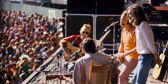 (LR) Stephen Stills, Neil Young, David Crosby i Graham Nash z Crosby Stills Nash & Young występują na scenie w Oakland Coliseum 13 lipca 1974 r. w Oakland w Kalifornii.