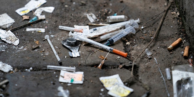 Syringes and paraphernalia used by drug users litter an alley.