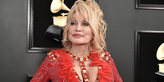 Dolly Parton in a red ruffled and sparkly dress with a bejeweled neck line at the Grammys