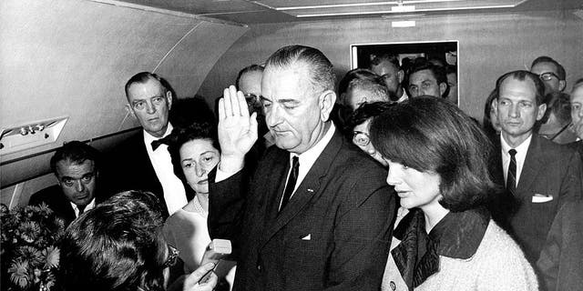 In the aftermath of the assassination of President John F. Kennedy, Vice-President Lyndon Baines Johnson (1908-1973) is shown taking the oath of office to become 36th president as he is sworn in by U.S. Federal Judge Sarah T. Hughes (1896-1985) (left) on the presidential aircraft, Air Force One, Dallas, Texas, Nov. 22, 1963. Kennedy's widow, Jacqueline Lee Bouvier Kennedy (later Onassis) stands beside him at right. 