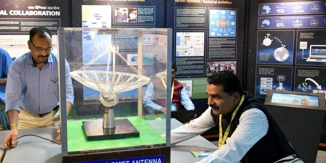 Un modelo organiza un modelo a escala de una antena de radiotelescopio gigante de ondas métricas (GMRT) en exhibición durante Vigyan Samagam, una exhibición científica masiva en múltiples lugares, en el Museo de Tecnología e Industria Visveswaraya en Bangalore el 29 de julio de 2019.