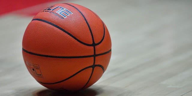 A ball lying on the court during a college basketball game. 