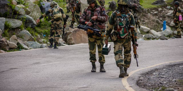 Indian Border Security Force soldiers patrol the area as an Indian army convoy passes through on a highway leading toward Leh, bordering China, in Gagangir, India, on June 19, 2020.