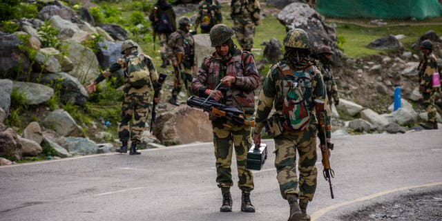 Indian Border Security Force soldiers patrol a highway as Indian army convoy passes through on a highway leading toward Leh, bordering China, on June 19, 2020 in Gagangir, India. 