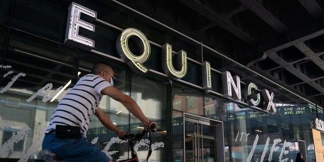 A man rides his bike past an Equinox gym on August 17, 2020, in New York.