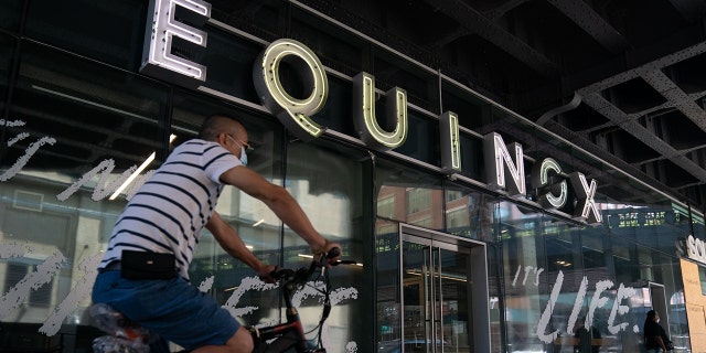 A man rides his bike past an Equinox gym on August 17, 2020, in New York.