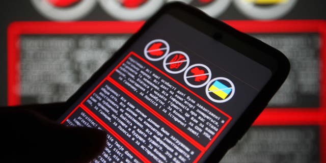This photo illustration shows a warning message in Ukrainian, Russian and Polish on a smartphone screen and in the background in Ukraine on January 14, 2022.