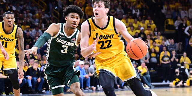 El alero de Iowa Patrick McCaffery, #22, se dirige a la canasta alrededor del portero Jaden Akins, #3, de los Michigan State Spartans, en la segunda mitad durante un partido de baloncesto universitario entre los Michigan State Spartans y los Iowa Hawkeyes el 22 de febrero de 2022, en Carver - Hawkeye Arena, Iowa City, Iowa.