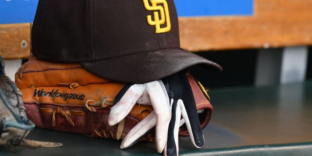 A detailed view of a San Diego Padres baseball hat and glove sitting in the dugout during the game against the Detroit Tigers at Comerica Park on July 25, 2022, in Detroit, Michigan.