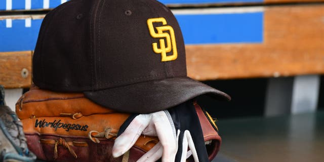 Una vista detallada de una gorra y un guante de béisbol de los Padres de San Diego sentados en el banquillo durante el partido contra los Tigres de Detroit en Comerica Park el 25 de julio de 2022, en Detroit, Michigan.