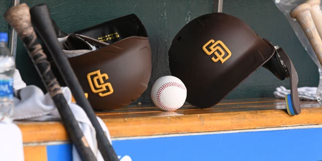 A detailed view of two San Diego Padres batting helmets and a baseball sitting in the dugout during a game against the Detroit Tigers at Comerica Park on July 25, 2022, in Detroit, Michigan.