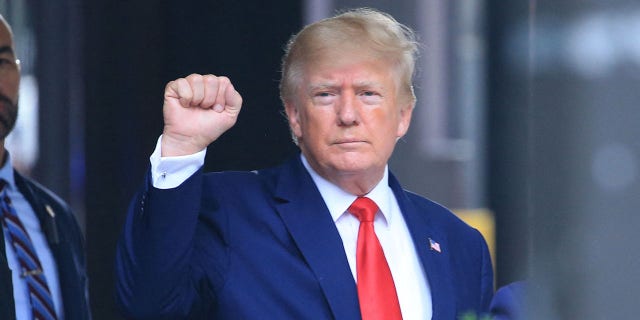 Former US President Donald Trump raises his fist while walking to a vehicle outside of Trump Tower in New York City on August 10, 2022.