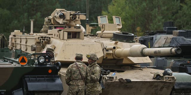 British soldiers chat next to US Abrams tanks, on the second day of joint military exercises at the training ground in Nowa Deba, Poland on September 21, 2022. Widak/Anadolu Agency via Getty Images)