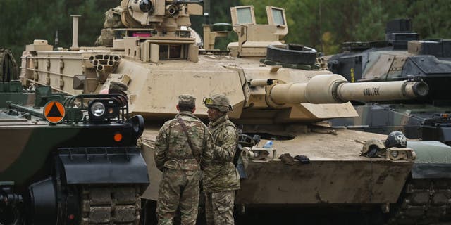 British soldiers chat next to U.S. Abrams tanks during joint military exercises in Nowa Deba, Poland, on Sept. 21, 2022. (Artur Widak/Anadolu Agency via Getty Images)