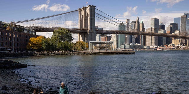 People take photos near Brooklyn Bridge Park in New York City on October 19, 2022. 