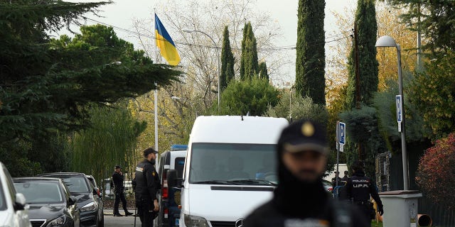 Spanish policemen stand next to an Ukrainian flag while securing the area after a letter bomb explosion at Ukraine's embassy in Madrid on November 30, 2022.