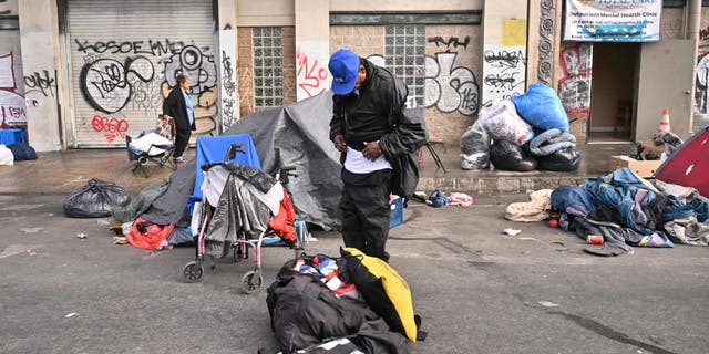 Homeless people stand with their belongings in front of an outpatient mental health clinic in Los Angeles, California, on Dec. 6, 2022. 