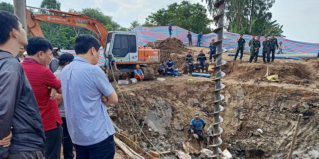Záchranári sa pozerajú na miesto, kde je 2. januára 2023 pravdepodobne uväznený 10-ročný chlapec v 35 metrov hlbokej šachte na stavbe mosta vo vietnamskej provincii Dong Thap. 