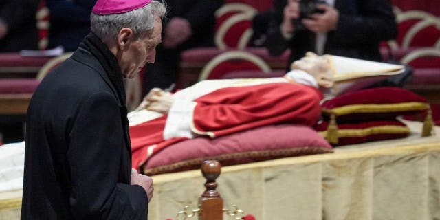 VATICAN - 2023/01/02: Archbishop Georg Gänswein prays in front of the body of Pope Emeritus Benedict XVI at St. Peter's Basilica. The Vatican announced that Pope Benedict died on December 31, 2022, aged 95. His funeral was held on January 5, 2023. 