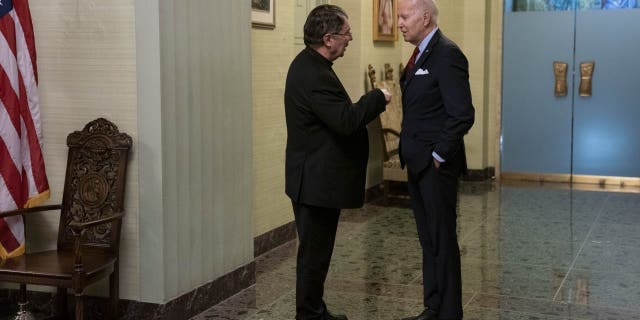 President Biden, right, speaks with Archbishop Christophe Pierre before signing the condolence book for Pope Emeritus Benedict XVI at the Apostolic Nunciature of the Holy See in Washington, D.C., Thursday, Jan. 5, 2023.