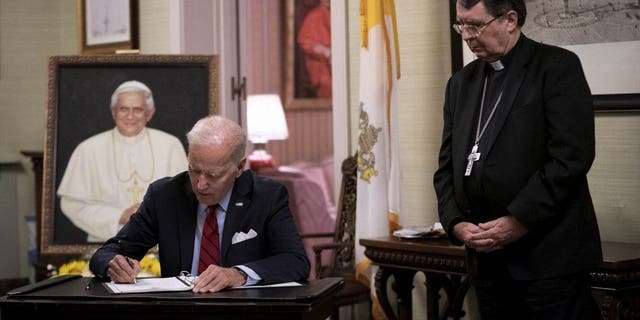 President Biden, left, signs the condolence book for Pope Emeritus Benedict XVI with Archbishop Christophe Pierre at the Apostolic Nunciature of the Holy See in Washington, D.C., Thursday, Jan. 5, 2023.