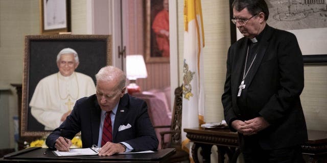 President Biden, left, signs the condolence book for Pope Emeritus Benedict XVI with Archbishop Christophe Pierre at the Apostolic Nunciature of the Holy See in Washington, D.C., Thursday, Jan. 5, 2023.